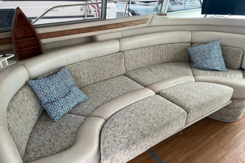 Slide: The Image of Luxurious interior of 1996 Sea Ray 370 Sedan Bridge with elegant curved seating and decorative pillows. - 4