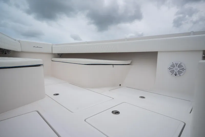 Slide: The Image of 2016 SeaHunter 45 boat interior with white seating and storage compartments under cloudy sky. - 15