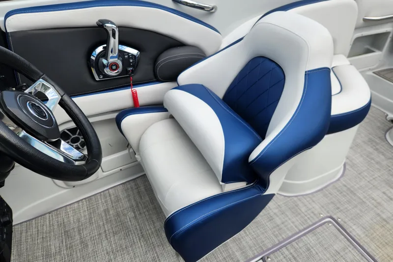 Slide: The Image of 2024 Crownline Eclipse E240 XS boat interior with blue and white captain's seat and steering wheel. - 14