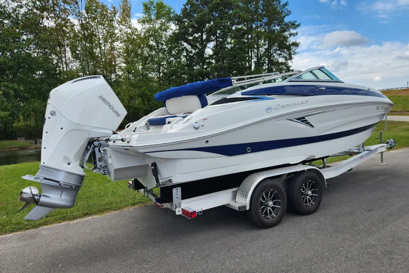 Slide: The Image of 2024 Crownline Eclipse E240 XS boat on trailer, parked outdoors, with Mercury outboard motor. - 2