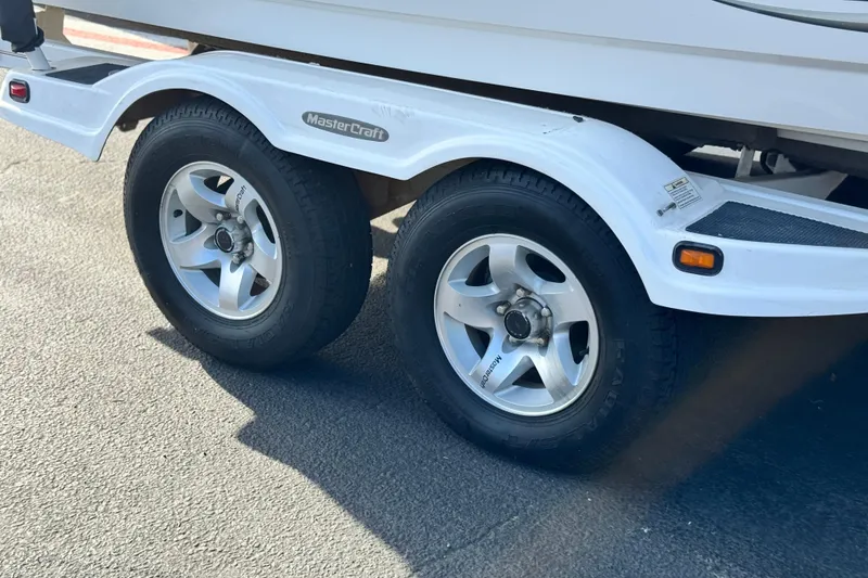 Slide: The Image of 2002 MasterCraft MariStar 230 VRS trailer wheels on pavement, showcasing dual tires. - 26