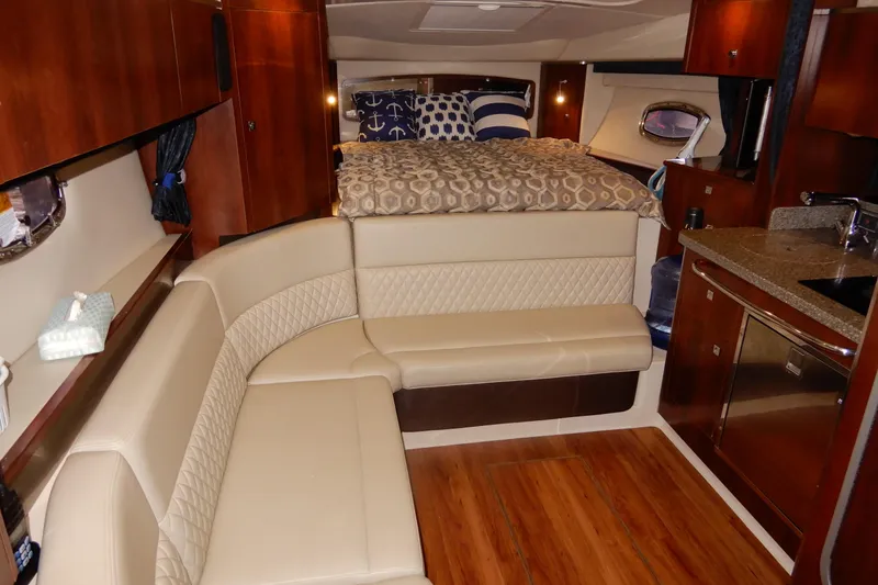 Slide: The Image of 2016 Chaparral 310 Signature cabin interior with beige seating, wood accents, and a cozy bed. - 30