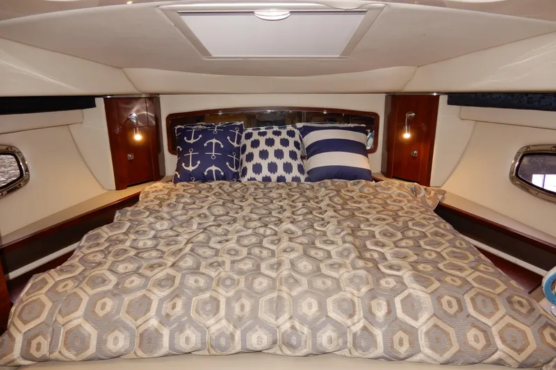 Slide: The Image of 2016 Chaparral 310 Signature cabin with cozy bed and nautical-themed pillows. - 31