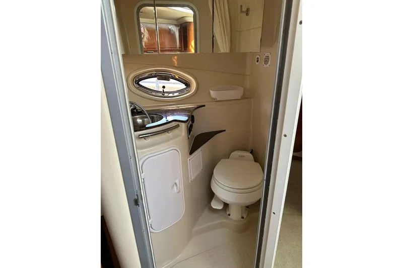Slide: The Image of 2006 Four Winns 318 Vista boat bathroom with toilet, sink, and oval window. - 11