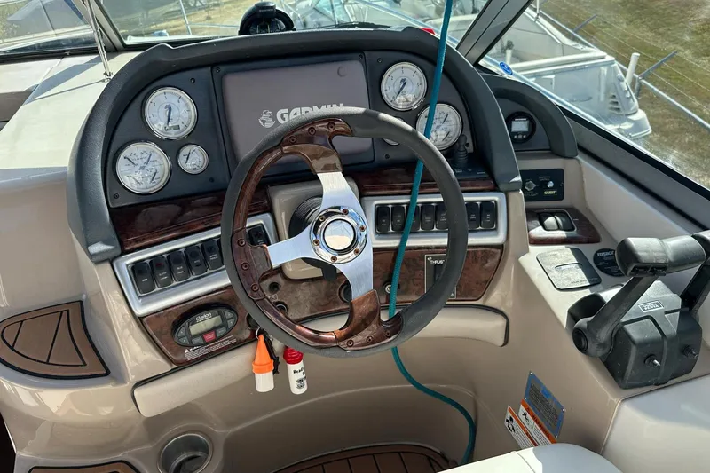 Slide: The Image of 2006 Four Winns 318 Vista boat dashboard with Garmin navigation and wood-accented steering wheel. - 3