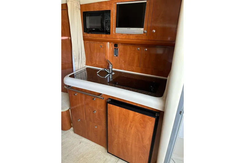 Slide: The Image of 2006 Four Winns 318 Vista boat kitchen with wood cabinets, sink, microwave, and mini-fridge. - 4