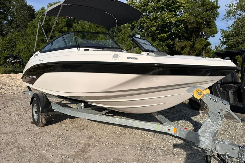 Slide: The Image of 2025 Yamaha Boats SX190 on trailer, parked outdoors with trees in background. - 1
