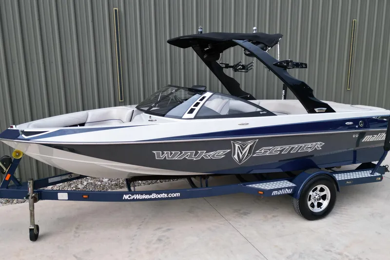 The Image of 2009 Malibu Wakesetter VTX boat on trailer, parked outdoors, side view. - 1