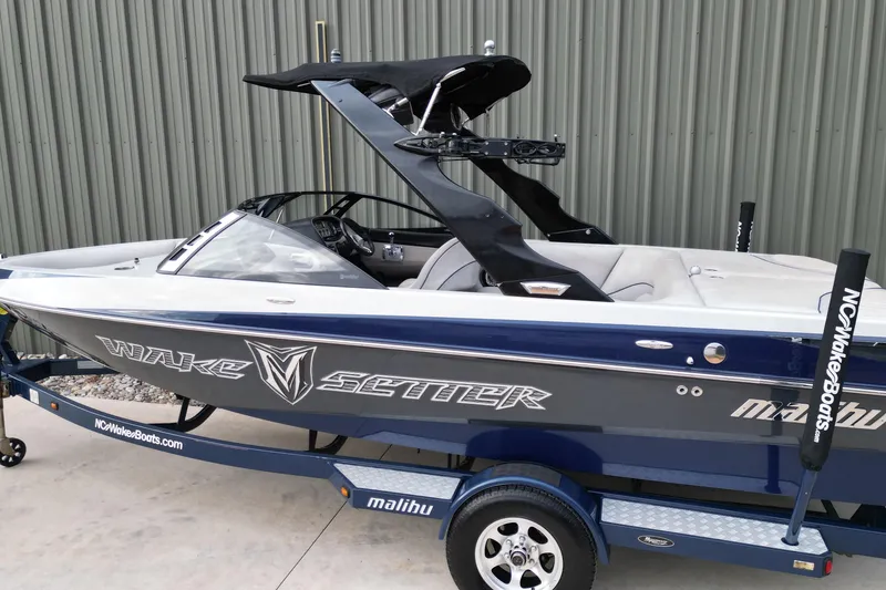 Slide: The Image of 2009 Malibu Wakesetter VTX boat on trailer, blue and white design, parked outdoors. - 3