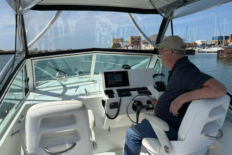 Slide: The Image of Man steering 2019 Albemarle 25 Express boat in marina, clear day. - 12