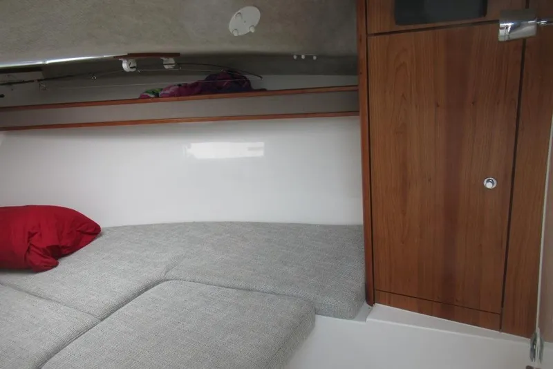 Slide: The Image of 2019 Albemarle 25 Express cabin interior with wooden cabinet, gray cushions, and red pillow. - 16