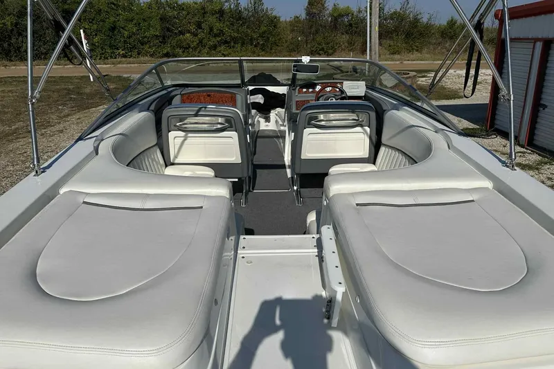 Slide: The Image of 2005 Cobalt 262 boat interior with white seating and dashboard, parked outdoors. - 2