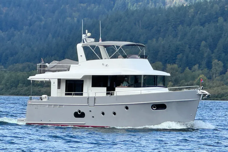 The Image of 2014 Beneteau Swift Trawler 50 cruising on a scenic lake with forested hills. - 0