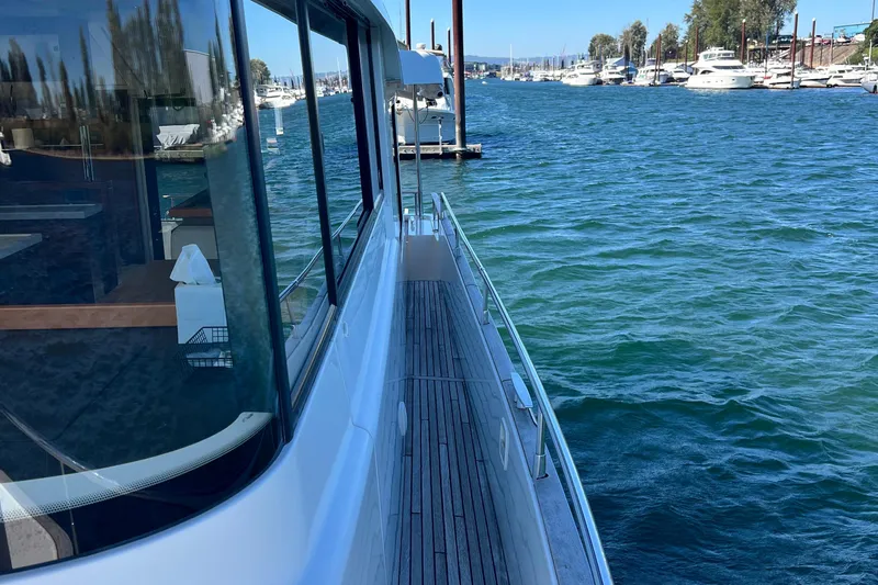 Slide: The Image of 2014 Beneteau Swift Trawler 50 on water, docked near marina, clear blue sky. - 15