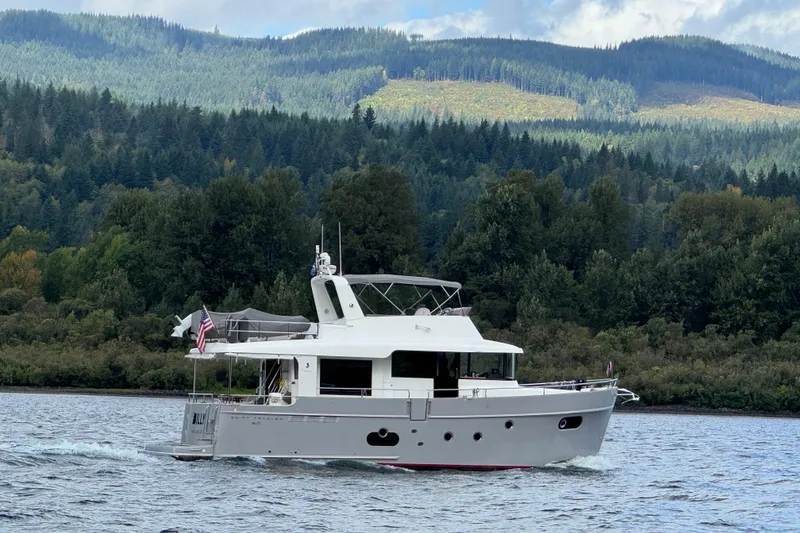 Slide: The Image of 2014 Beneteau Swift Trawler 50 cruising on a scenic lake with forested hills. - 2