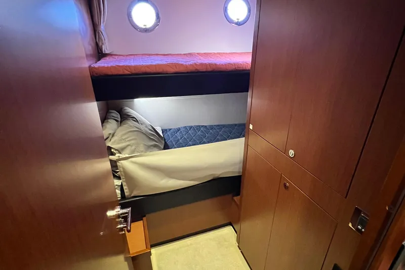 Slide: The Image of Bunk beds in 2014 Beneteau Swift Trawler 50 cabin with wooden interior and porthole. - 40