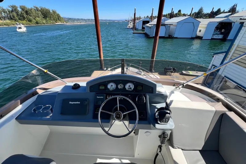 Slide: The Image of 2014 Beneteau Swift Trawler 50 helm with Raymarine navigation, docked near marina. - 46