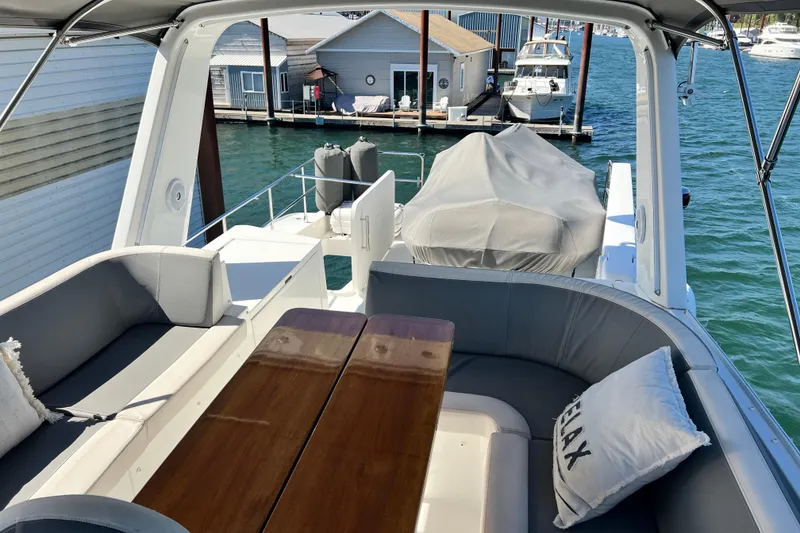 Slide: The Image of 2014 Beneteau Swift Trawler 50 deck with seating, table, and marina view. - 50