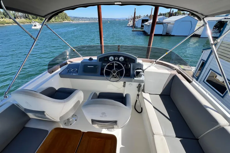 Slide: The Image of 2014 Beneteau Swift Trawler 50 helm with dual seats, overlooking marina and water. - 51