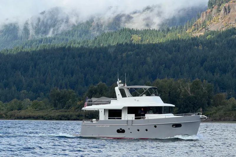 Slide: The Image of 2014 Beneteau Swift Trawler 50 cruising on a scenic lake with forested hills. - 54