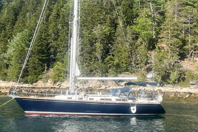 Slide: The Image of 1987 Sabre 42 K/CB sailboat anchored near a forested shoreline. - 0