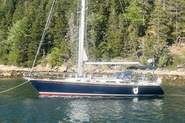 Slide: The Image of 1987 Sabre 42 K/CB sailboat anchored near a forested shoreline. - 1