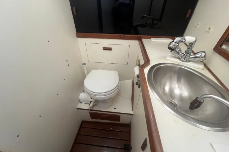 Slide: The Image of 1987 Sabre 42 K/CB yacht bathroom with toilet, sink, and wooden accents. - 42