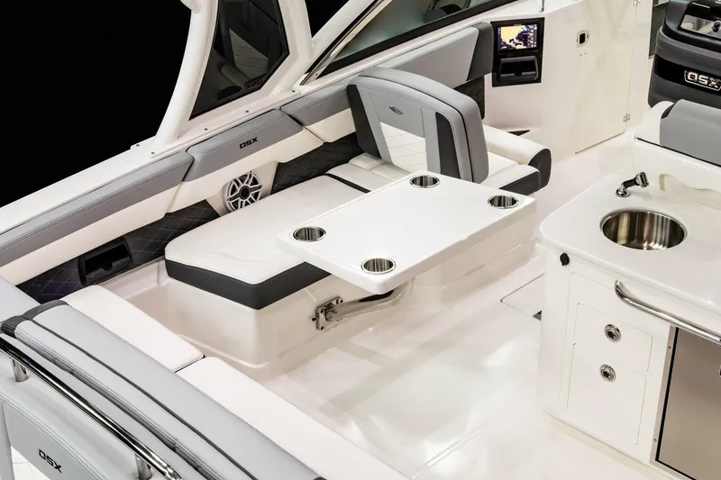 Slide: The Image of 2026 Chaparral 310 OSX boat interior with seating, table, and kitchenette. - 17