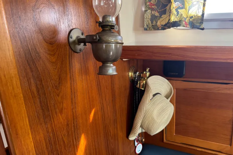 Slide: The Image of Interior of 1988 Nonsuch 36 sailboat with vintage lamp and hat on wooden wall. - 32