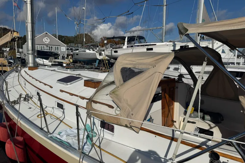 Slide: The Image of 1988 Nonsuch 36 sailboat docked at marina, featuring beige canopy and wooden accents. - 38