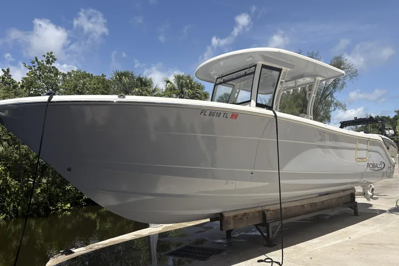 Slide: The Image of 2023 Robalo R302 Center Console boat on a dock under a clear blue sky. - 4