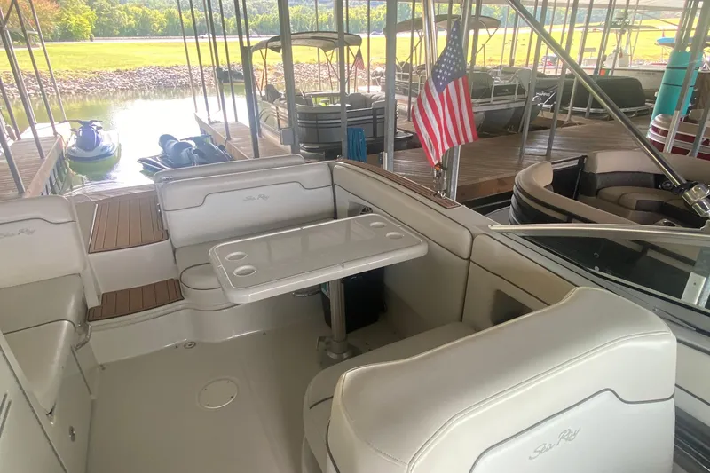 Slide: The Image of 2008 Sea Ray 290 Sundeck interior with seating, table, and American flag at dock. - 11