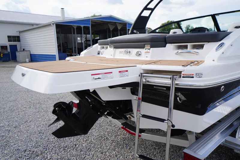 Slide: The Image of 2026 Chaparral 21 SSi boat with swim platform and ladder, parked on gravel. - 40