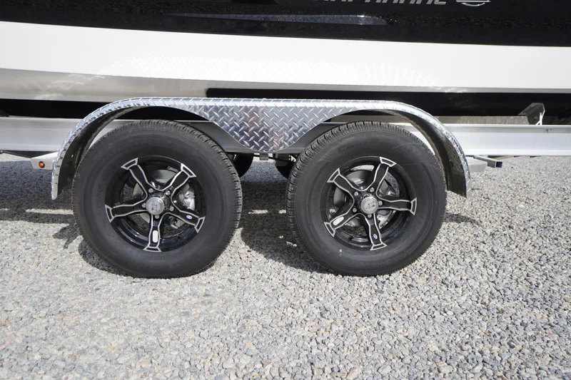 Slide: The Image of 2026 Chaparral 21 SSi boat trailer with dual black alloy wheels on gravel. - 44