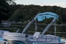 Slide: The Image of 2019 Qwest LS 714 Lanai Cruise pontoon boat on a serene lake with forested background. - 2