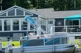 Slide: The Image of 2019 Qwest LS 714 Lanai Cruise boat docked near a lakeside house. - 4