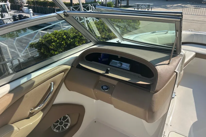 Slide: The Image of 2011 Cobalt 242 boat interior with dashboard and speaker, docked near greenery. - 17