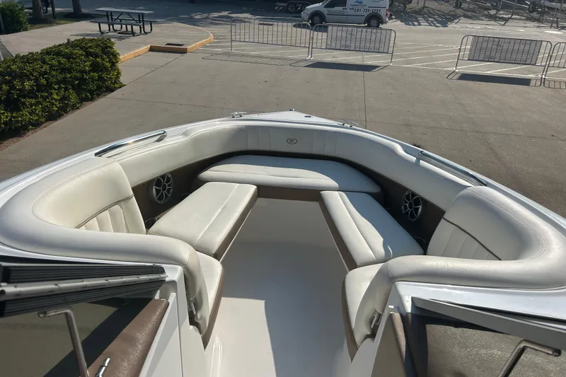 Slide: The Image of 2011 Cobalt 242 boat interior with white seating and speakers, parked outdoors. - 18