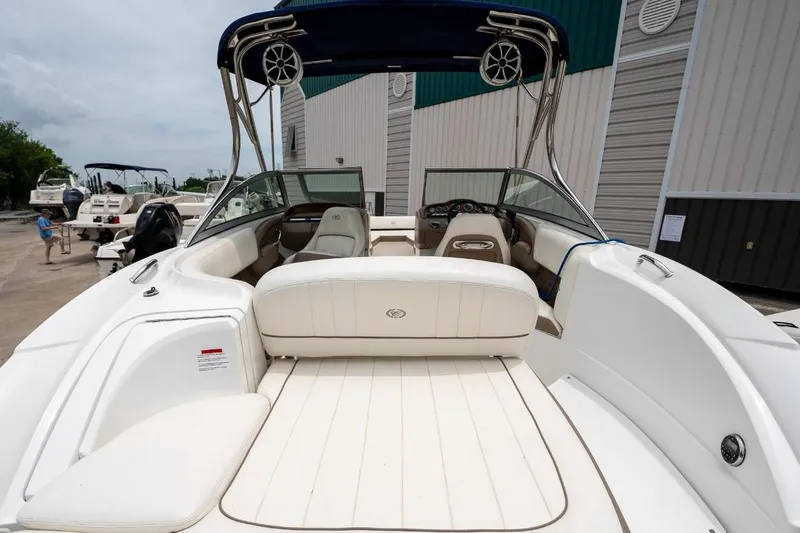 Slide: The Image of 2011 Cobalt 242 boat interior with white seating and dashboard, docked outdoors. - 27