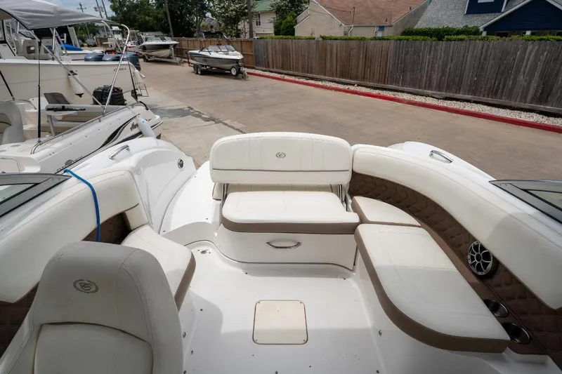 Slide: The Image of 2011 Cobalt 242 boat interior with white and brown seating, docked in a marina. - 28