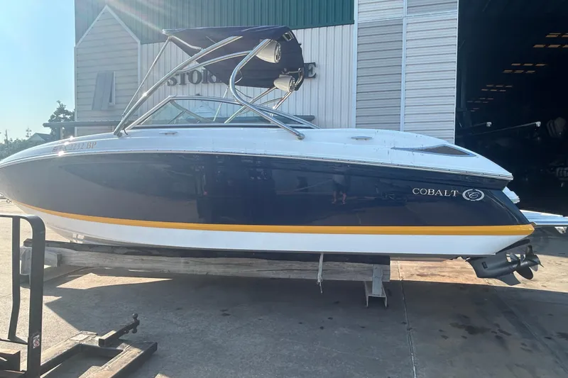 Slide: The Image of 2011 Cobalt 242 boat with blue and white exterior, parked outside a storage facility. - 5