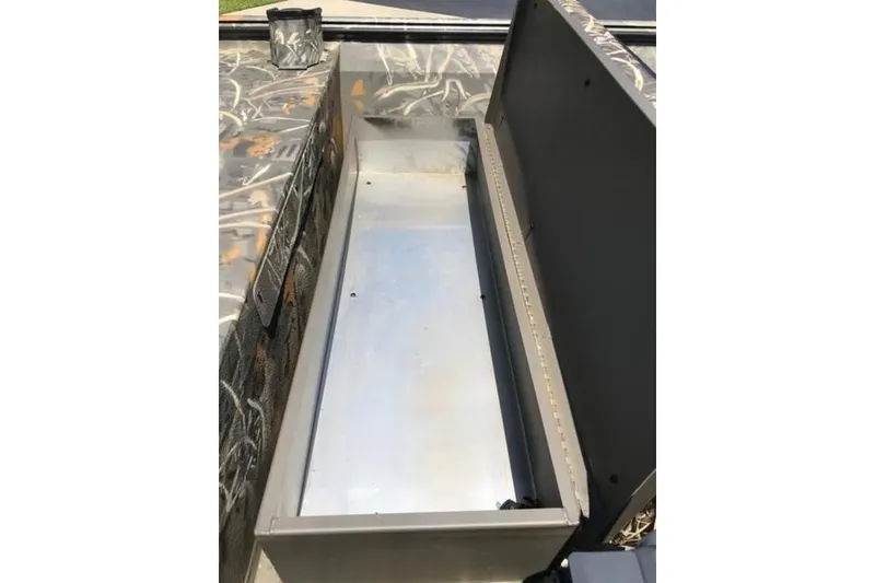 Slide: The Image of Open storage compartment in 2026 War Eagle 754LDSV boat, featuring camo design. - 4