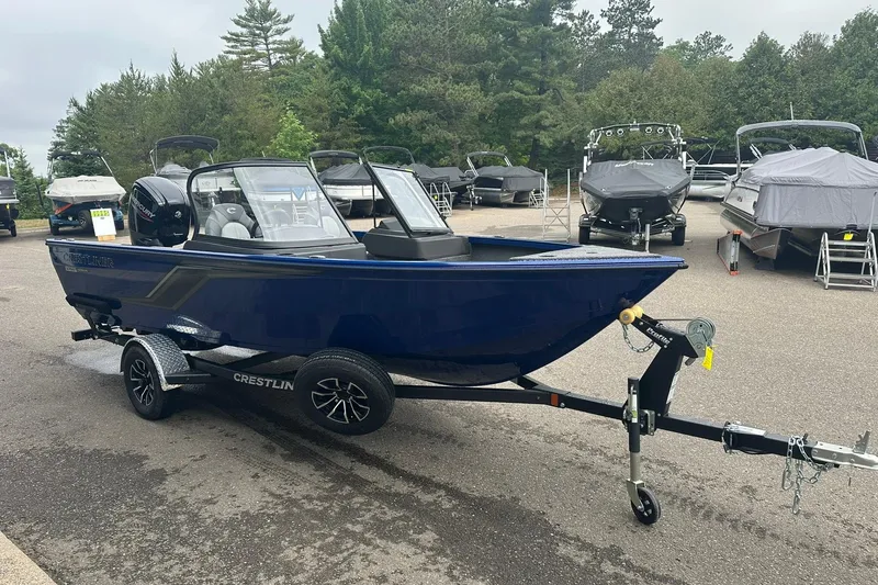 Slide: The Image of 2025 Crestliner 1750 Hawk boat on trailer, parked outdoors with other boats in background. - 4