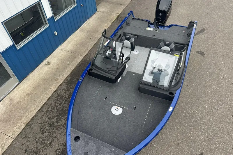 Slide: The Image of 2025 Crestliner 1750 Hawk boat, blue exterior, dual consoles, spacious interior, parked near building. - 9