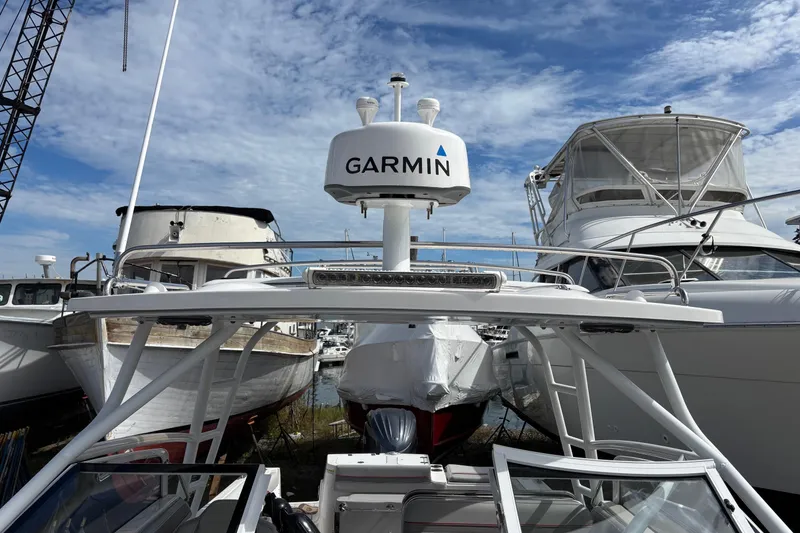 Slide: The Image of 2024 Solara S-250 DC boat with Garmin radar, docked among other vessels under a blue sky. - 7