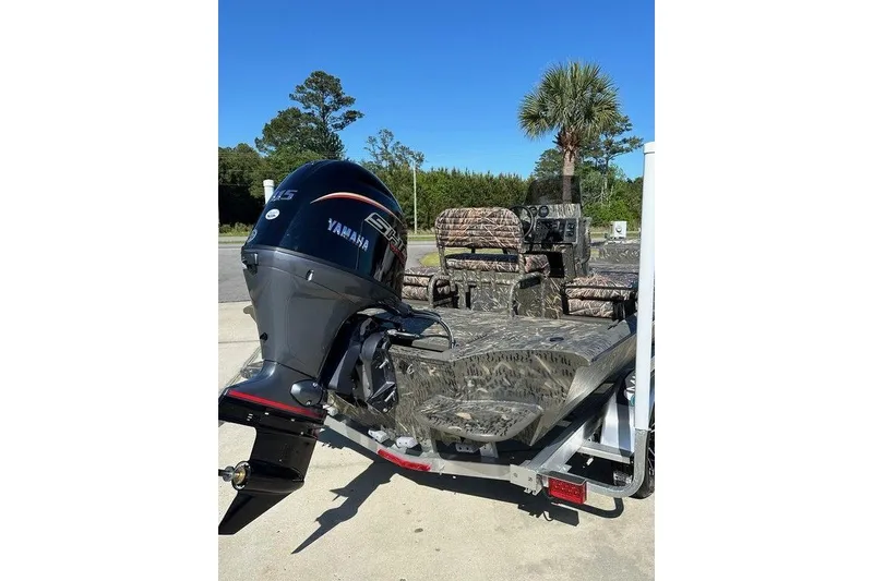 Slide: The Image of 2026 War Eagle Blackhawk 961 boat with Yamaha engine, camo design, parked outdoors. - 10