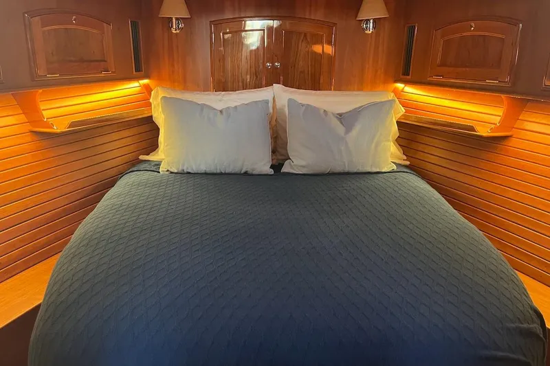 Slide: The Image of Luxurious cabin interior of 2013 Hinckley Talaria 48 MY with cozy bedding and warm lighting. - 28