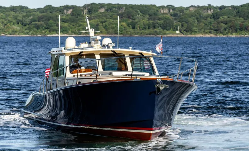 Slide: The Image of 2013 Hinckley Talaria 48 MY cruising on open water with lush green shoreline. - 3