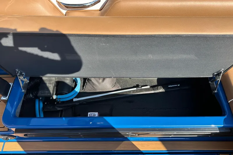 Slide: The Image of 2022 Moomba Makai storage compartment with brown leather seating and blue interior accents. - 11