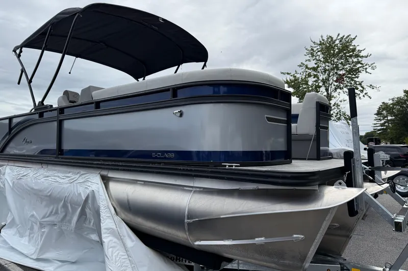 Slide: The Image of 2026 Qwest Splash Pad E-Class pontoon boat with canopy, parked on trailer. - 9